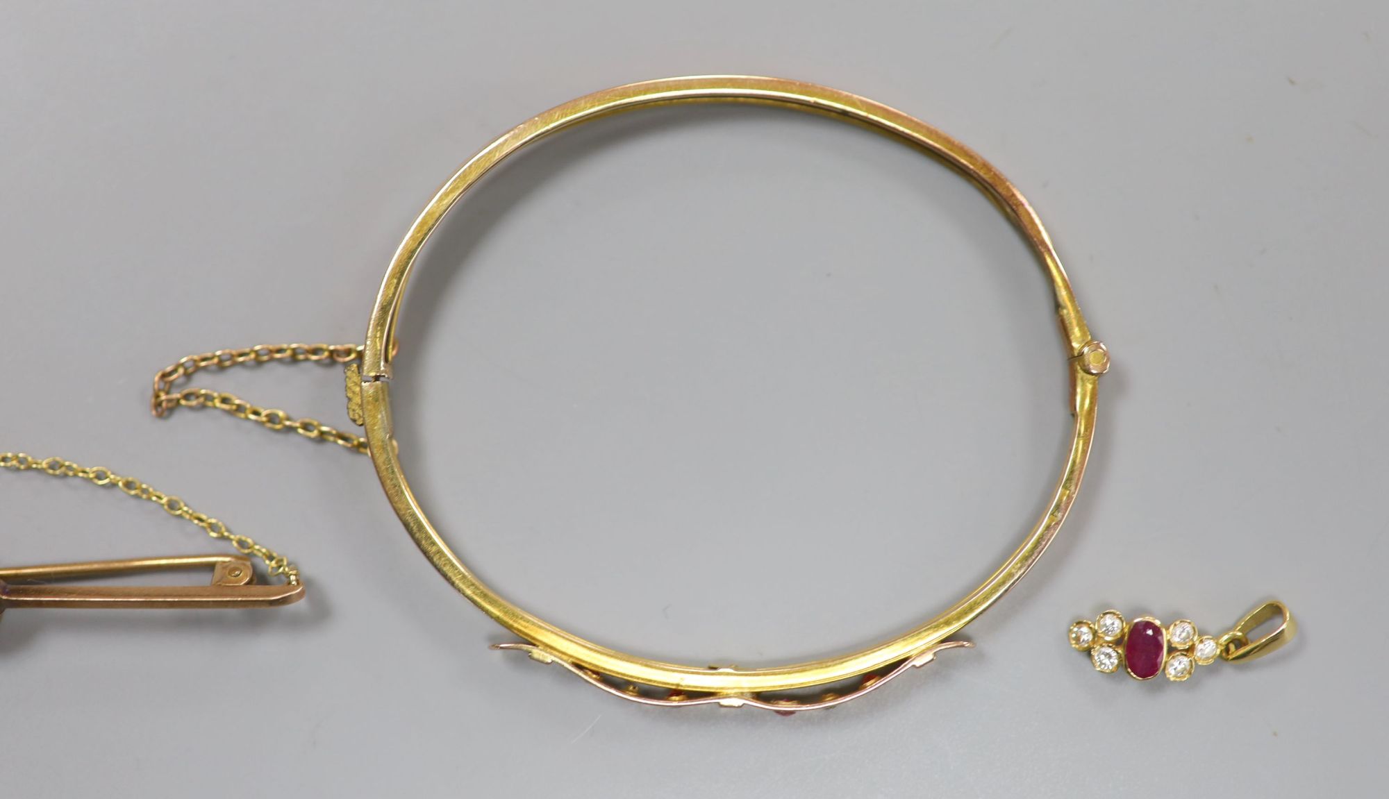 An Edwardian yellow metal, ruby and diamond set hinged bangle(a.f.) gross 5.2 grams, pendant and brooch.